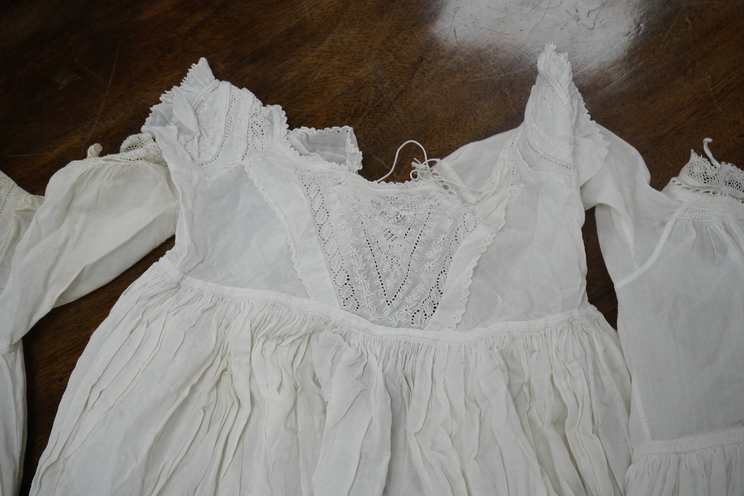 Two late 19th early 20th century long baby night gowns and two shorter baby gowns, together with a pink satin ladies full length slip and a similar cream silk stockinette slip, the bodices worked on baby dresses are embr